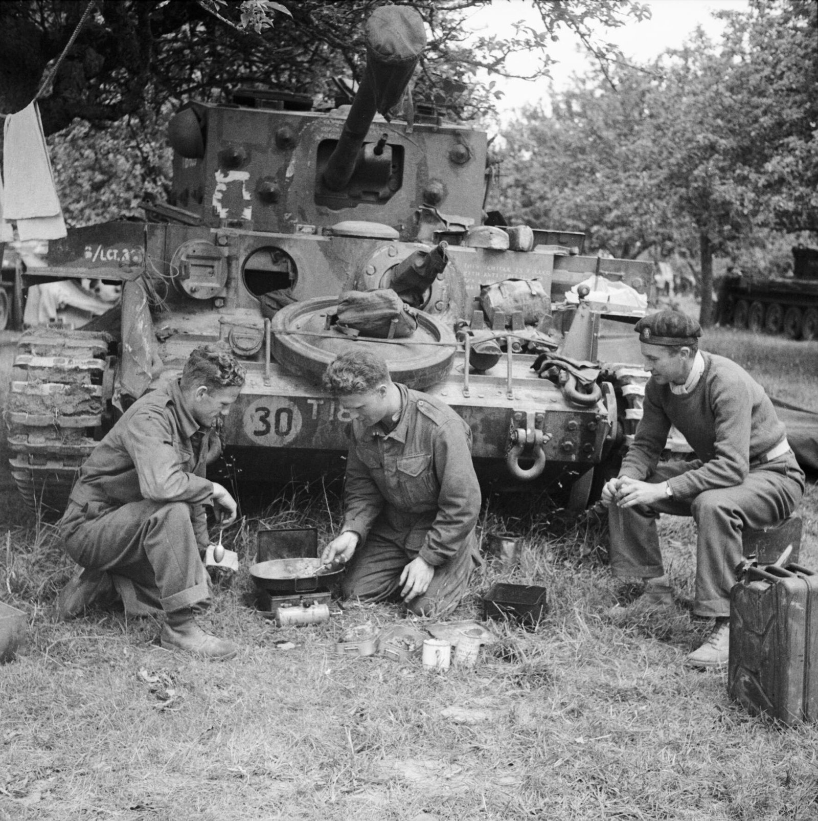 Cromwell tank crew of 4th County of London Yeomanry, 7th Armoured Division, preparing a meal beside their vehicle in Normandy, 17 June 1944. Human-context service image; crew identities are listed in archive metadata.