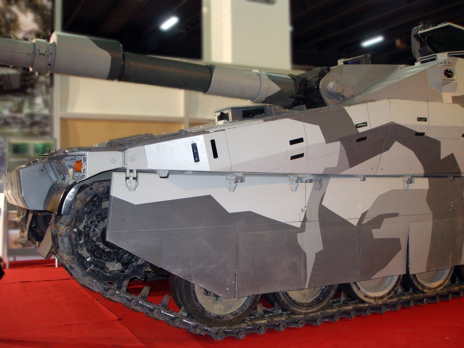 CV90120 side skirt and track detail at MSPO 2007. Side view detail showing the CV90-derived running gear, side armor/skirt arrangement, and 120 mm gun overhang. 5 September 2007. MSPO 2007 / International Defence Industry Exhibition, Kielce, Poland (event context). Shows chassis/running-gear discussion.